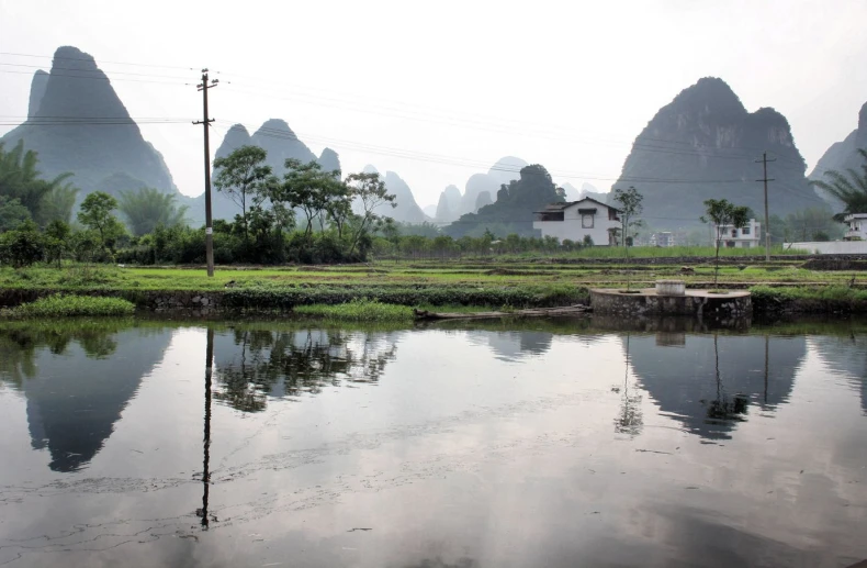 a mountain range is reflected in water near a small village