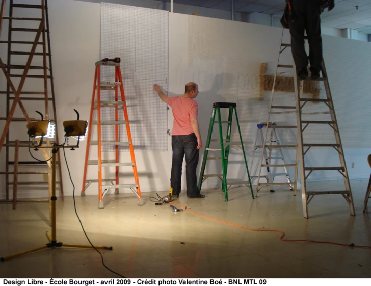 a man is using a ladder to paint a large white wall