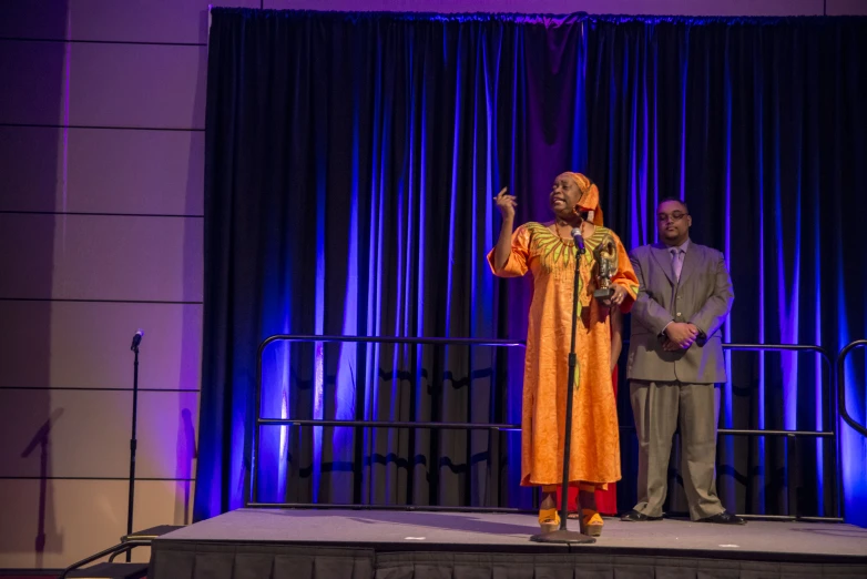 two men standing on stage with a curtain behind them