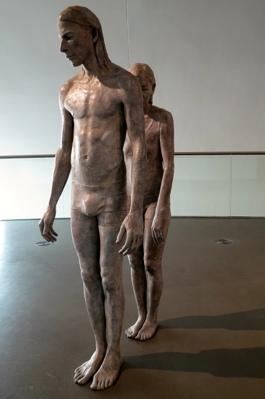 two sculptures are standing in an art gallery