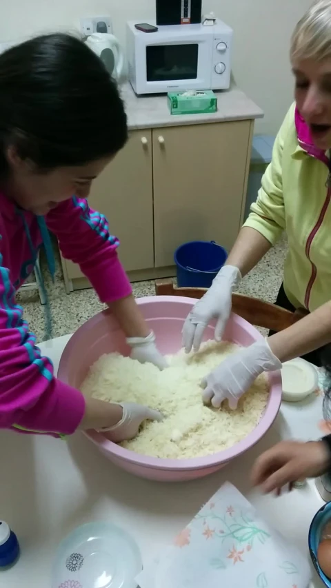 two ladies in a kitchen, one preparing dough for baking