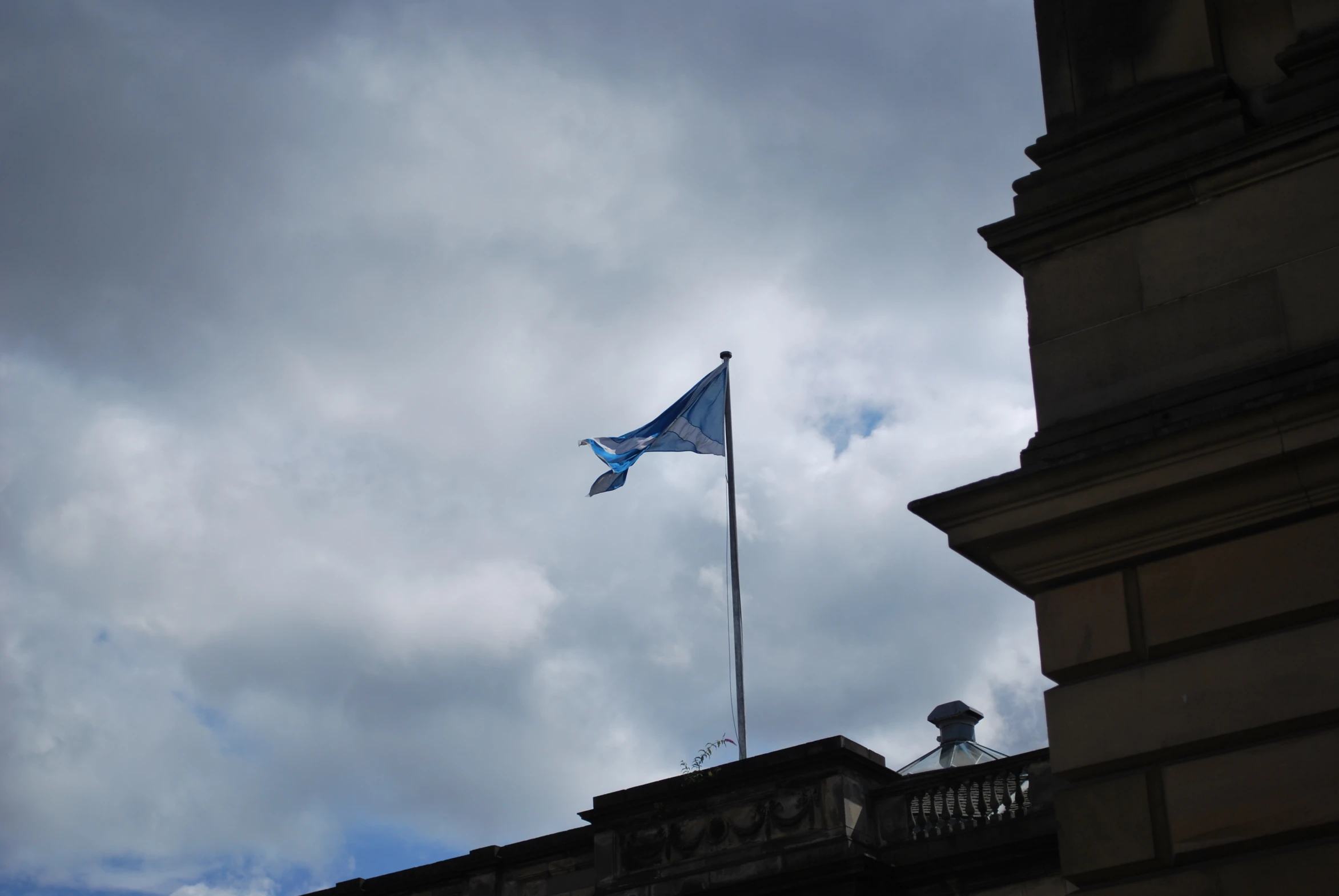 a flag flying high above the ground in a cloudy day