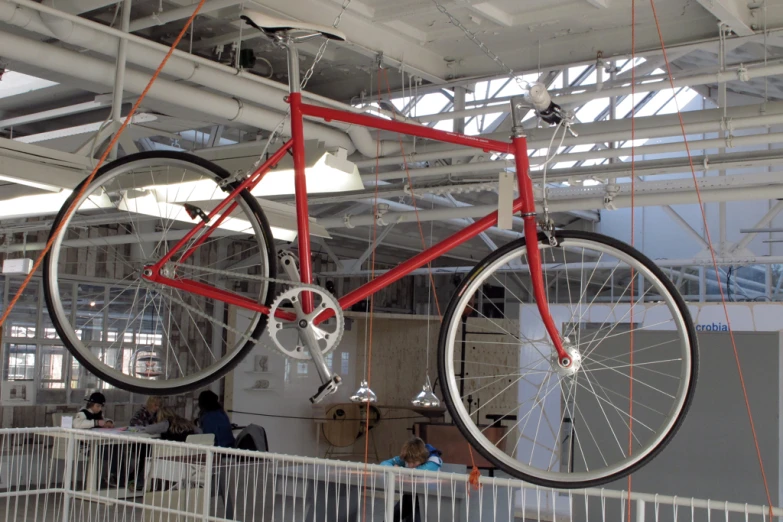 an artistic display of a red bike suspended from the ceiling