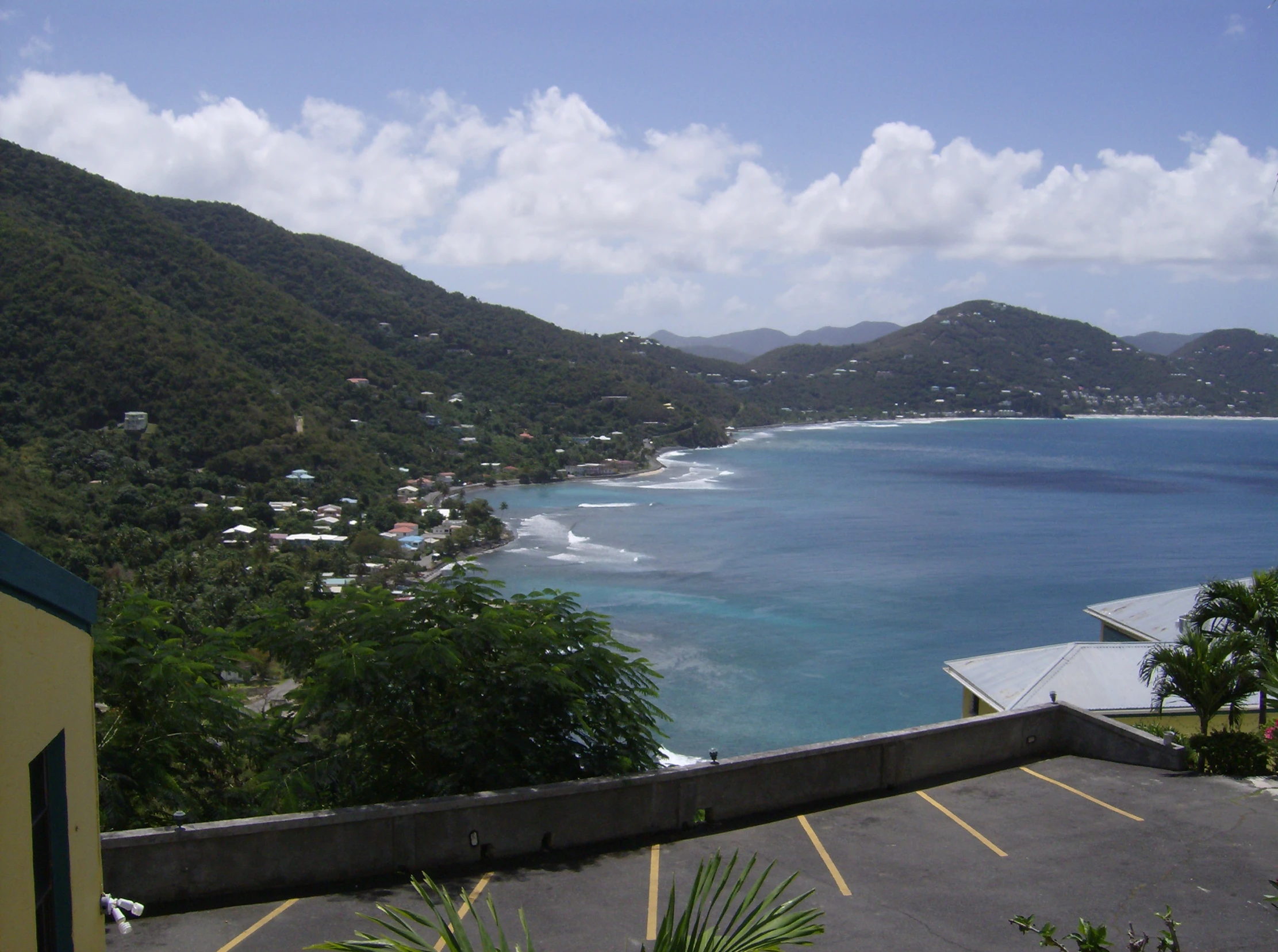 view from balcony overlooking the ocean with sand, trees and buildings