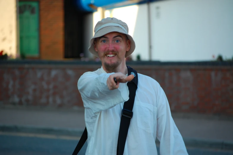 man in white shirt pointing at camera with a smile on his face