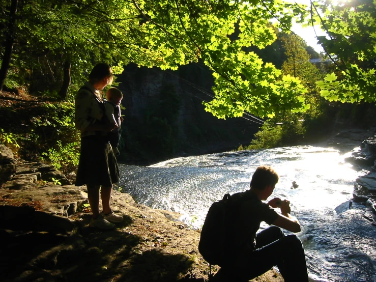 people are sitting next to a small river on the rocks