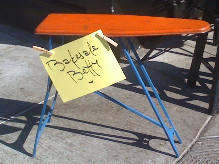 a sign for a surf board on an orange and blue metal stand