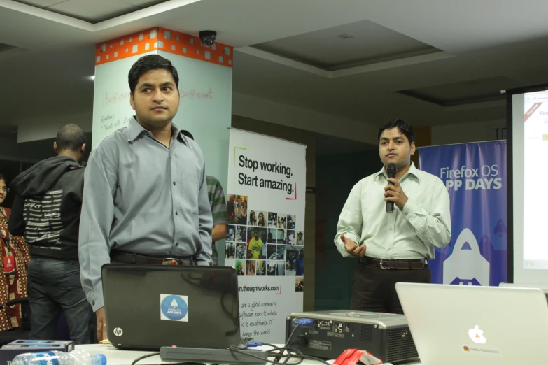 two men standing in front of two laptop computers