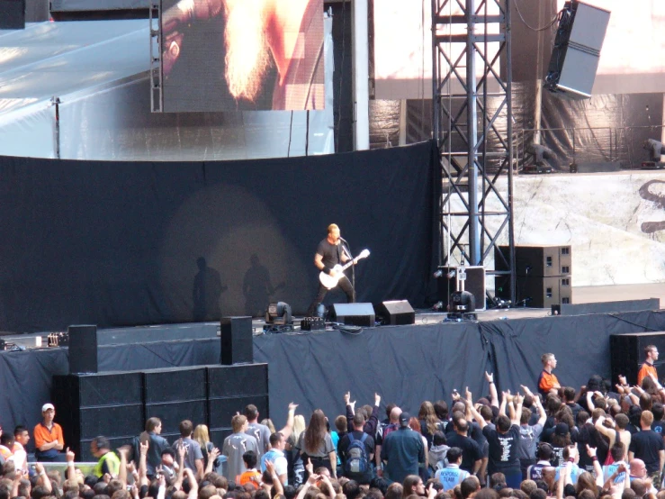 a person playing guitar in front of a large crowd