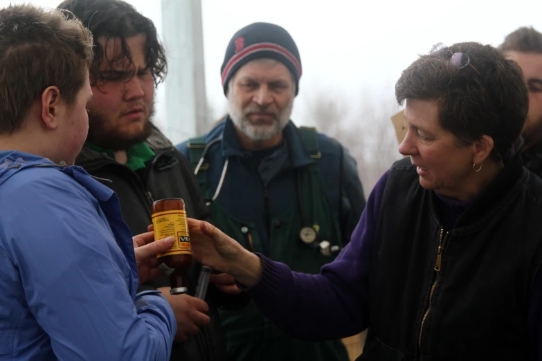 people are standing with one another holding a bottle of beer