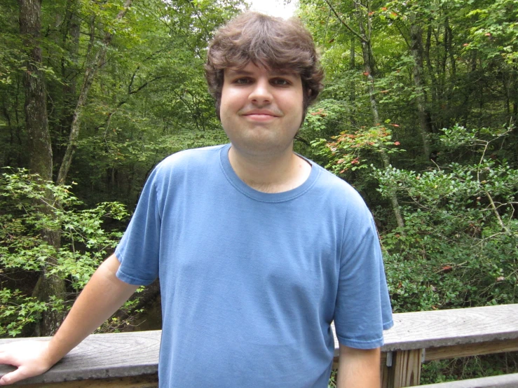 a man with his hand on his hip standing on a wooden rail