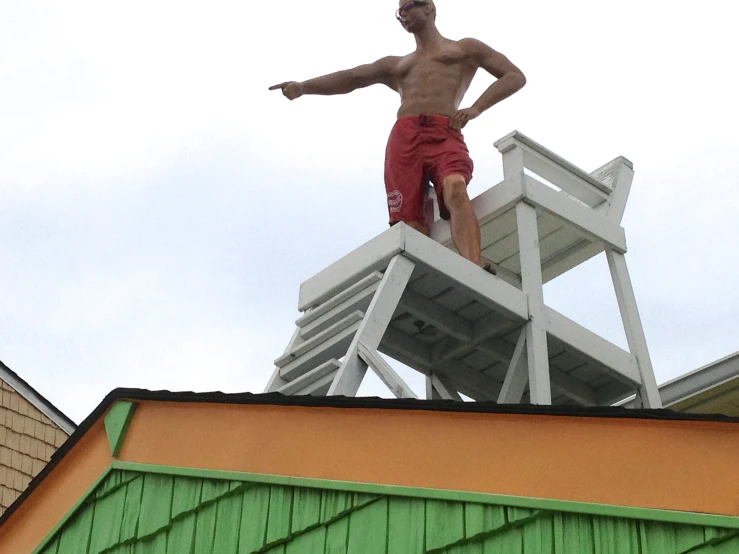 the man is standing atop a lifeguard chair