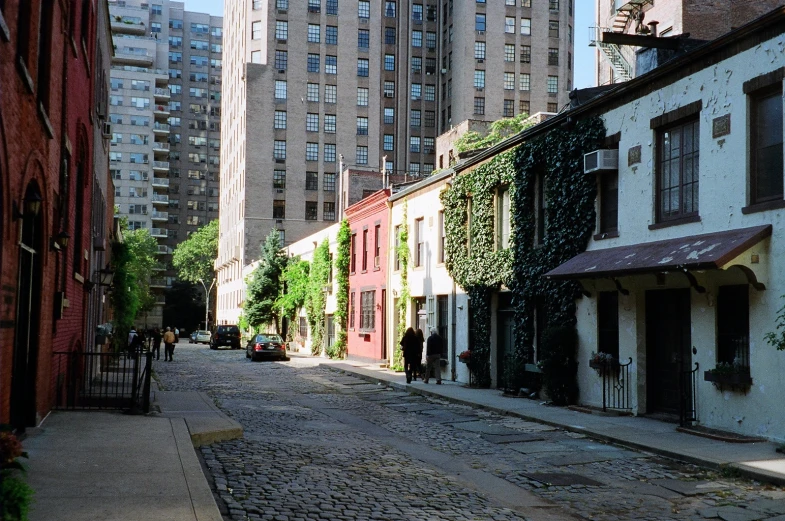 an alley with some red building and green ivy growing on the side