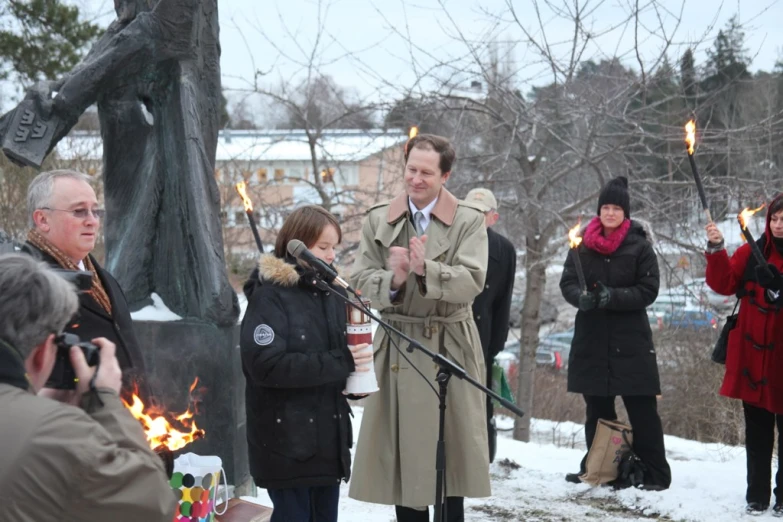 a group of people in coats singing at a public memorial