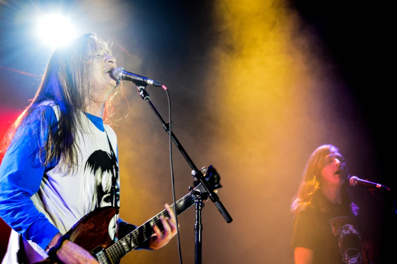 two people are performing on stage playing guitars