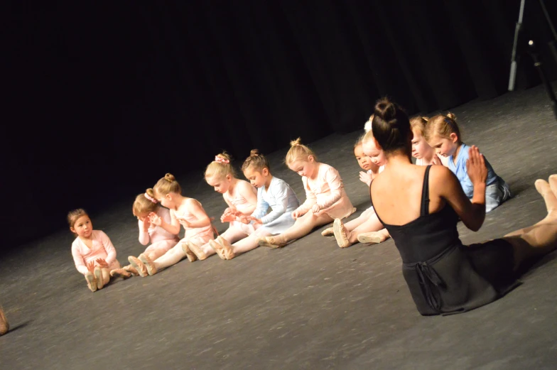 a bunch of girls in ballet clothes sitting and playing