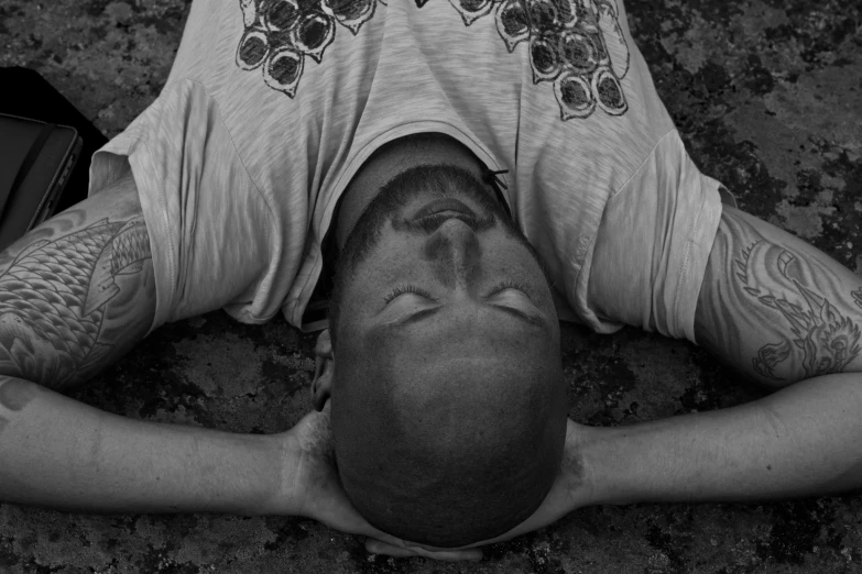 a man has tattoos on his face and arms while laying on the ground