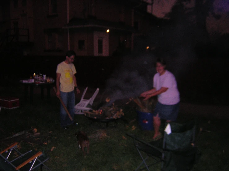 two men are cooking meat on top of an open fire pit