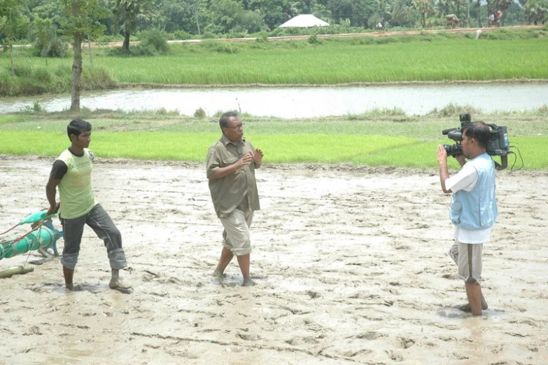 three people standing in the sand with one holding a camera