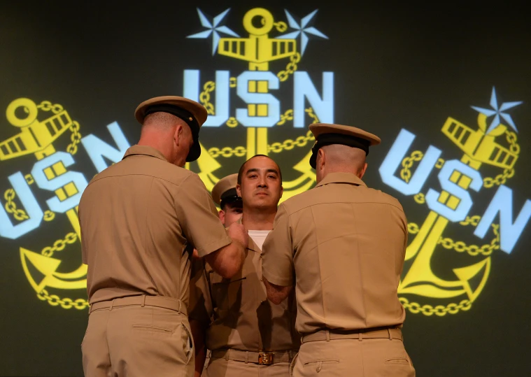 three military officers standing in front of the usn seal