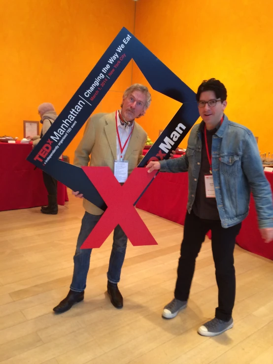 two men posing in front of an x shaped object