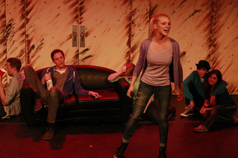 group of people posing on stage with red couch