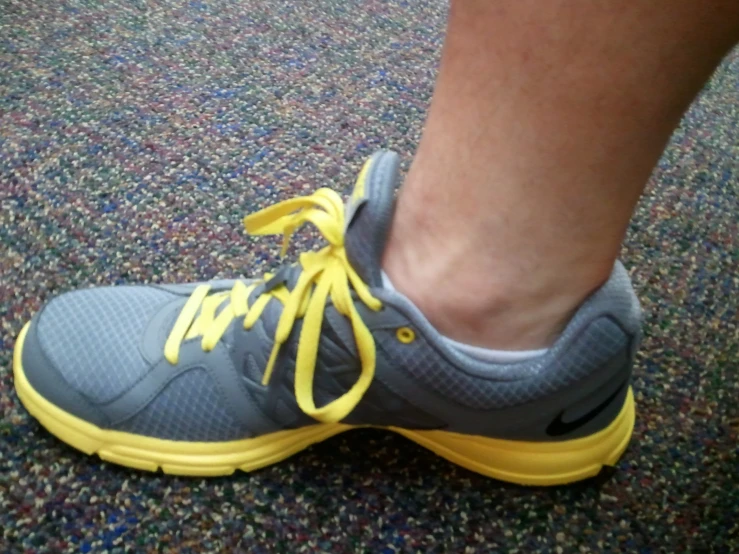 this is the foot of a man wearing yellow and gray shoes