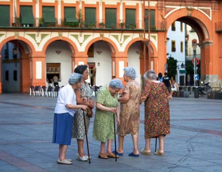 four women standing together talking in front of an orange building