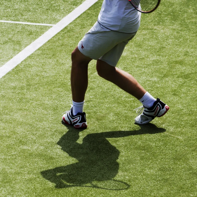 a man standing on top of a grass covered tennis court