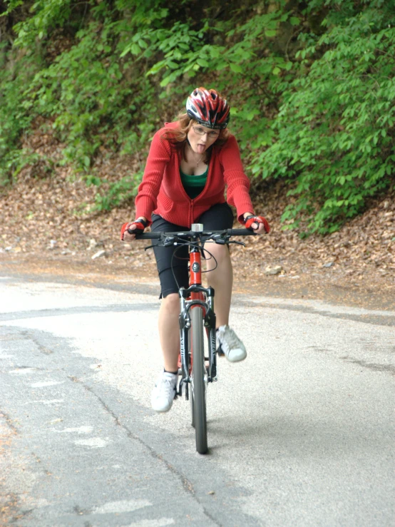 a woman in red riding her bike down a road