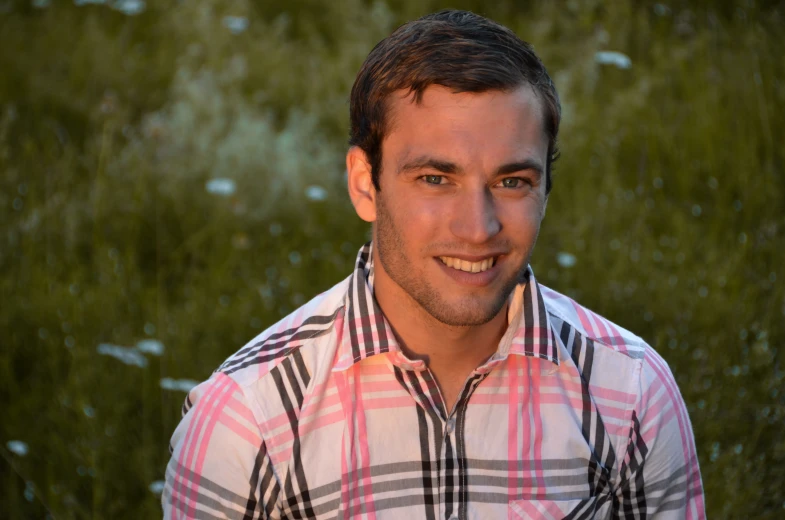 a young man with a plaid shirt posing for a portrait