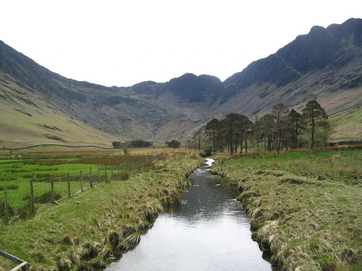 a river surrounded by mountains near a grassy area