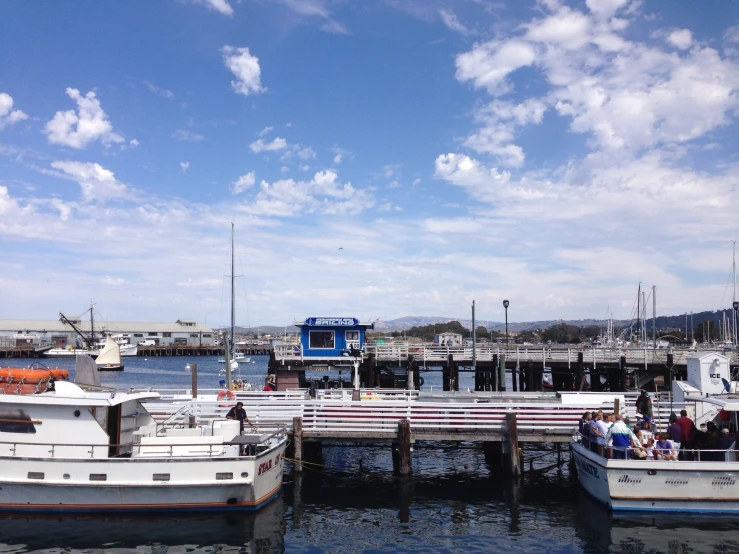 some boats docked at a small pier under a blue sky