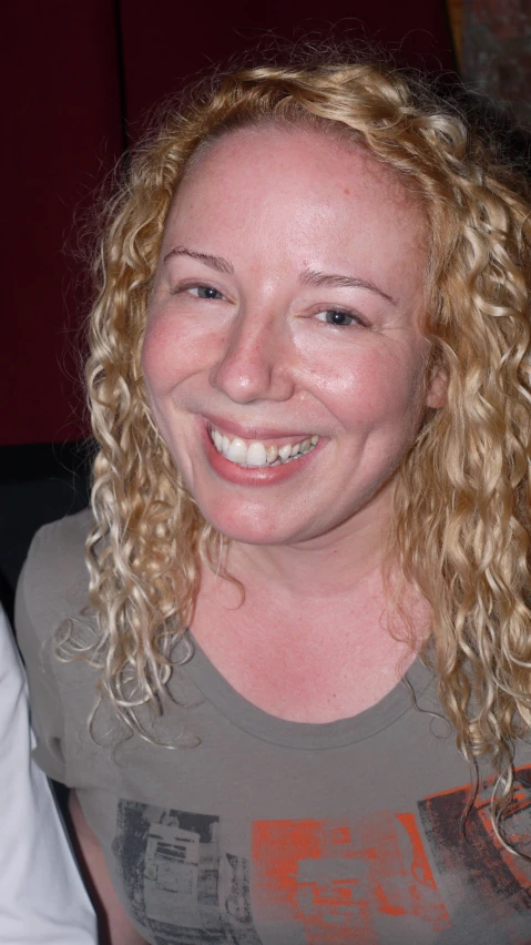 a woman with blond hair is smiling at the camera