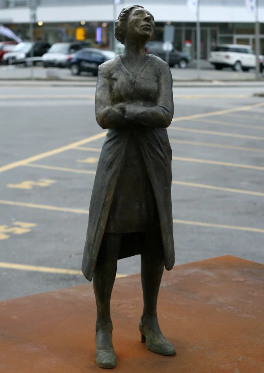 a bronze statue of a woman in the parking lot