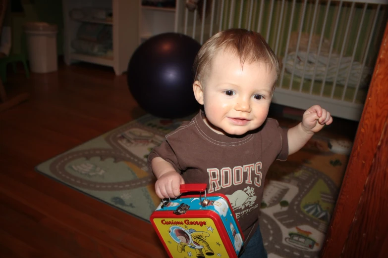 a toddler standing with his toy suitcase
