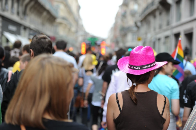 the girl wearing a pink cowboy hat is looking at people