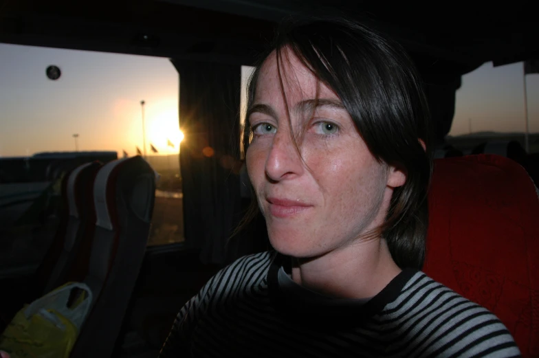 woman looks into the distance at sunset, while seated in front of a carnival ride