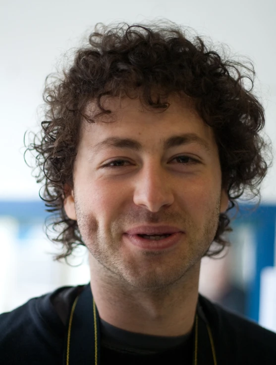 a man with curly hair smiles at the camera