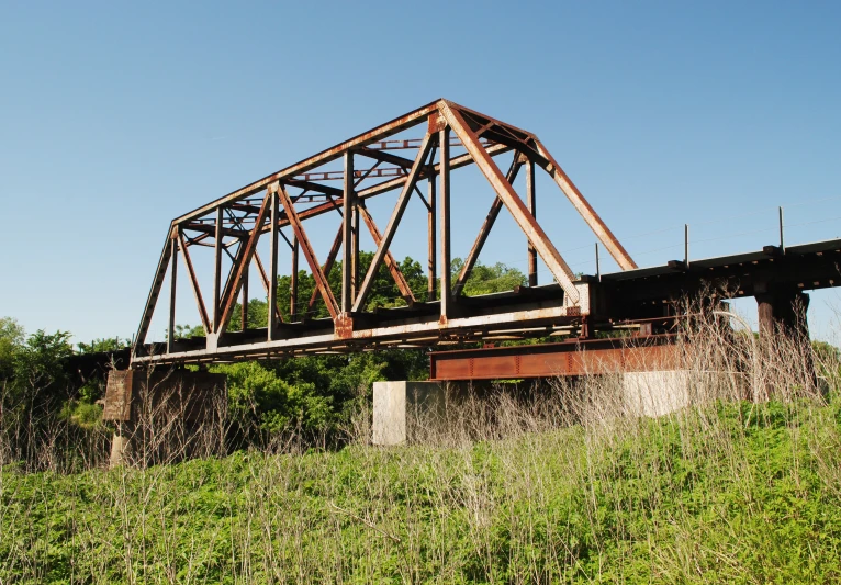 a run down bridge over some tall grass