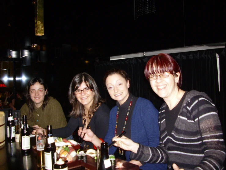 several women are smiling and eating with beer at a table