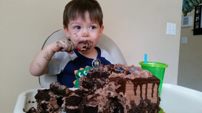 a young child eats an odd shaped chocolate cake