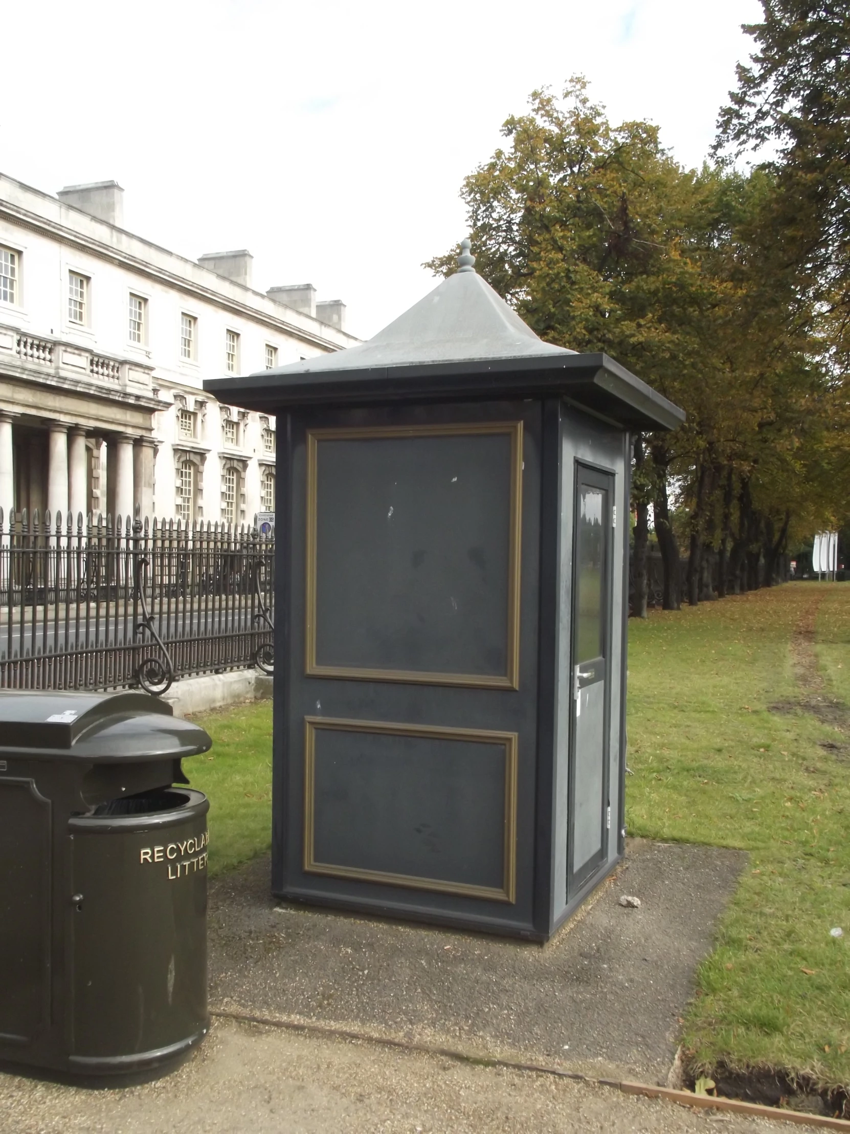 a toilet sits next to a trash can near some sort of mail box