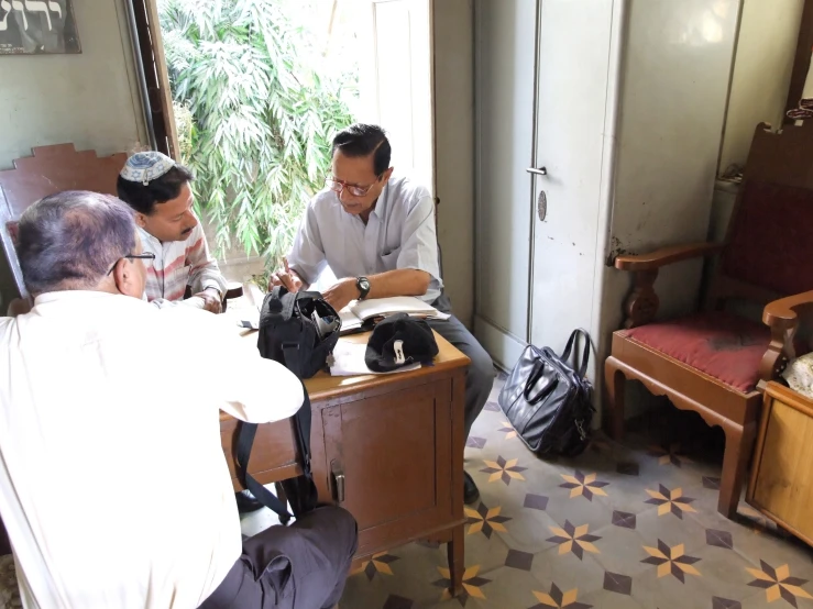 three people sit and talk in an open room with a table