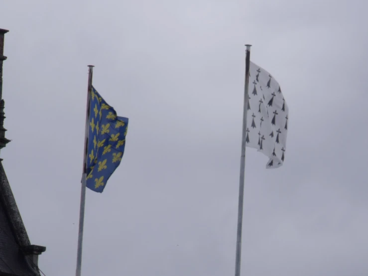 three flags flying in front of a building under cloudy skies