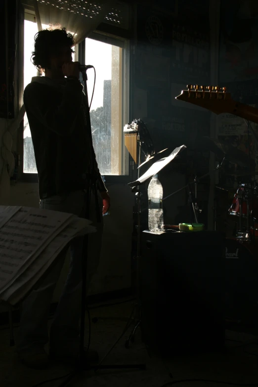 the musician stands beside a microphone near a set of keyboards