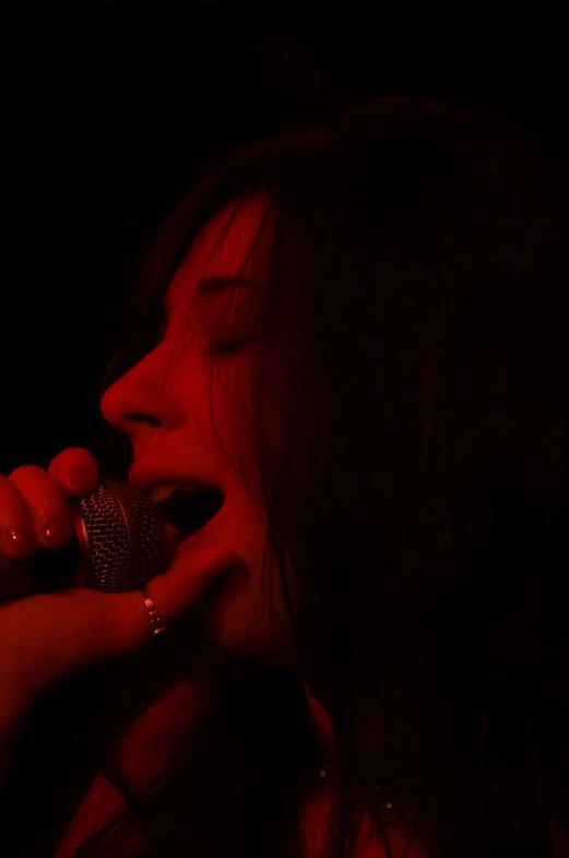 a woman that is in the dark with a microphone