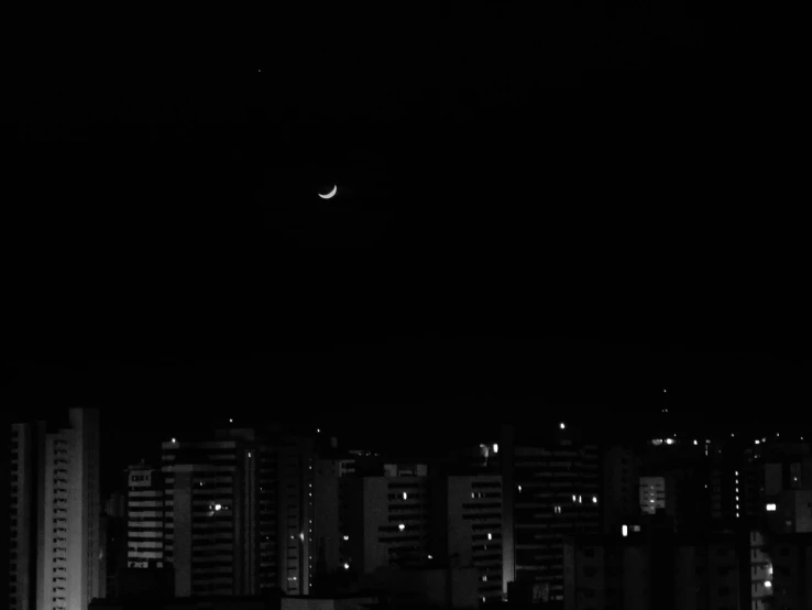 a view of a cityscape at night with the moon above