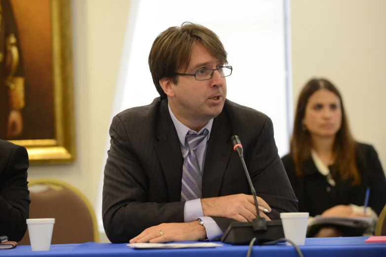 a man talking into a microphone in front of people