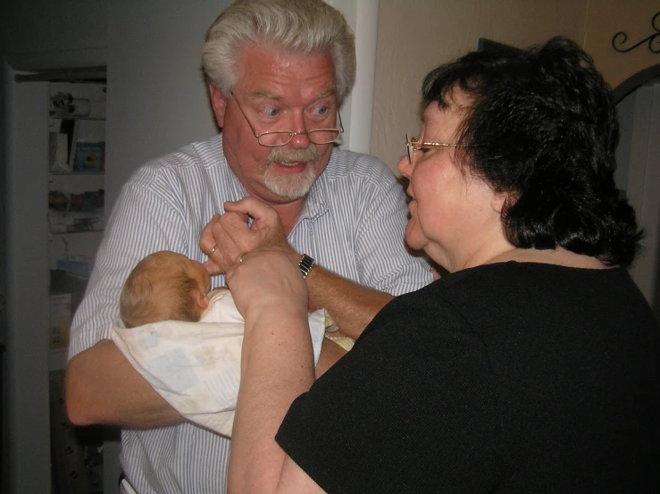 man and woman are holding a baby wearing glasses